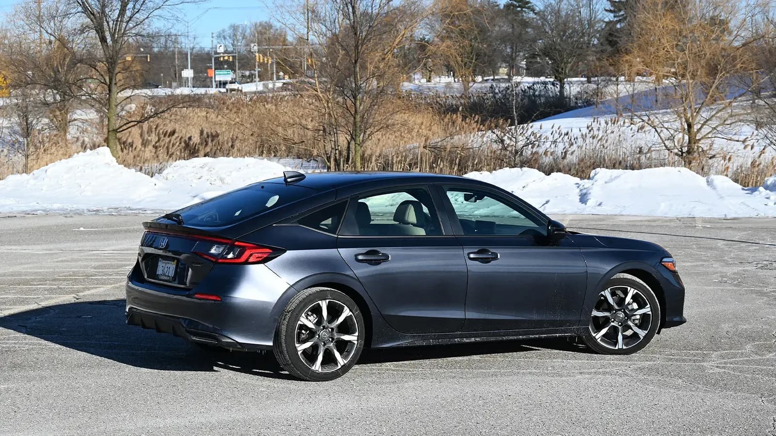 A dark blue 2026 Honda Civic Sport Touring Hybrid three quarter rear view