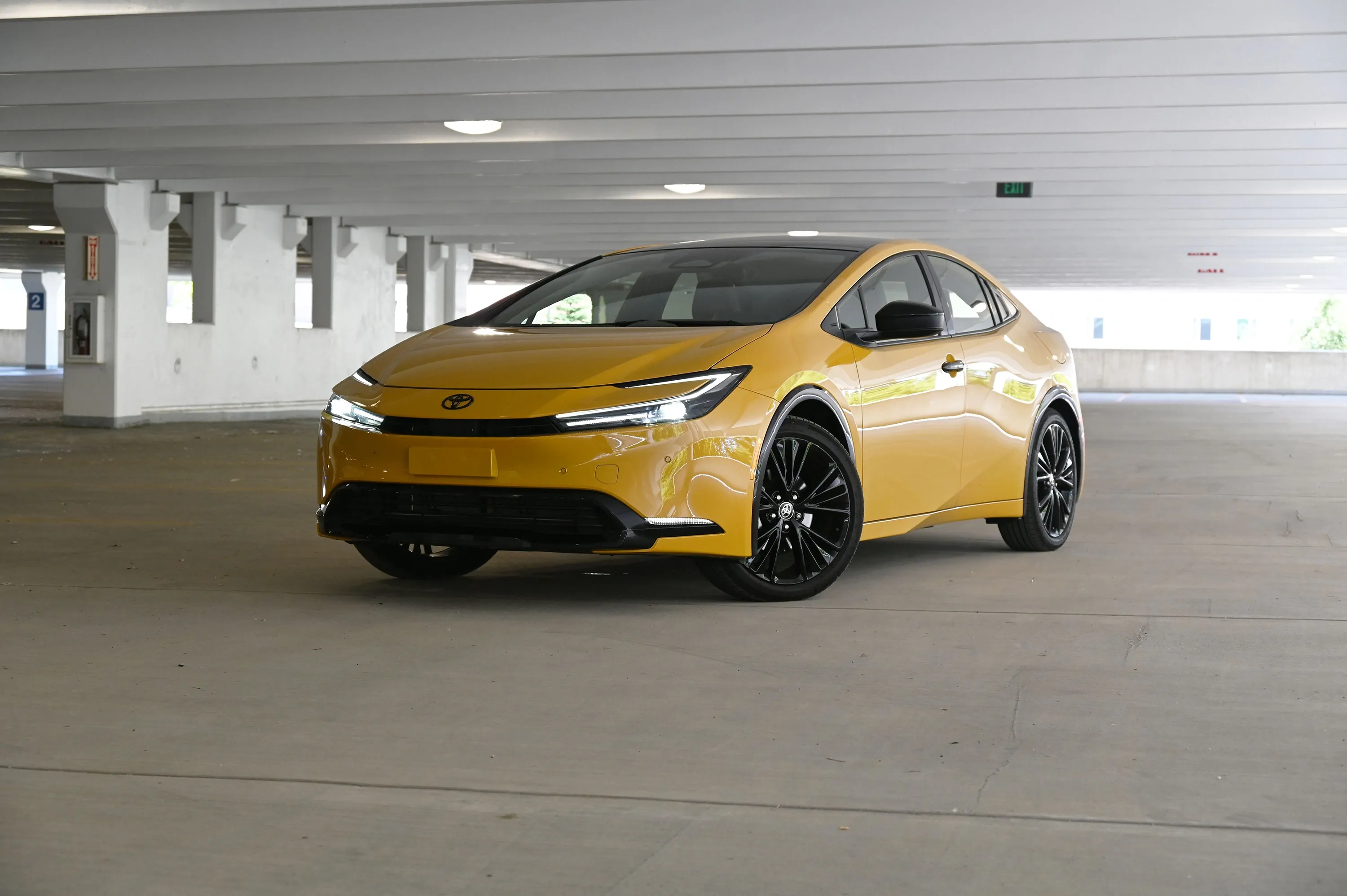 Front three-quarter view of a gold Toyota Prius in a parking garage.
