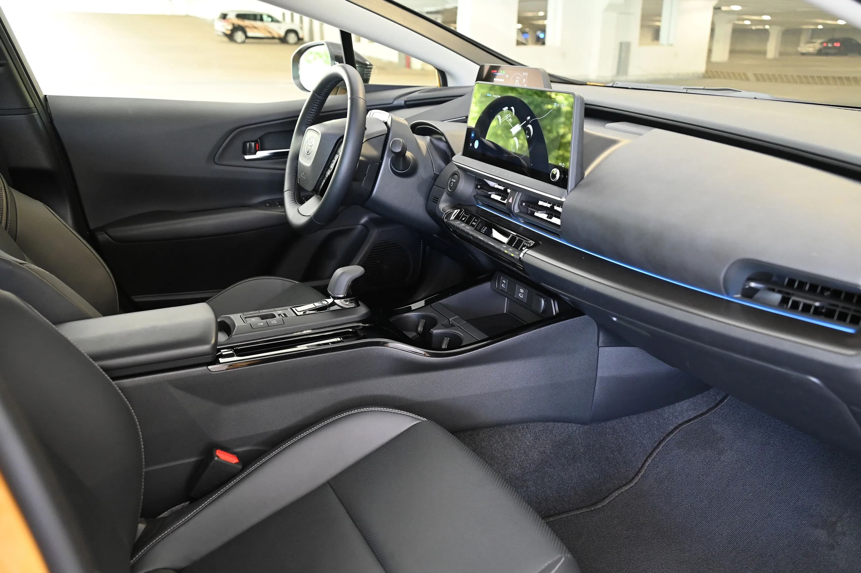 Front passenger view of the Toyota Prius cabin with the dashboard, center console, and wireless charging pad.