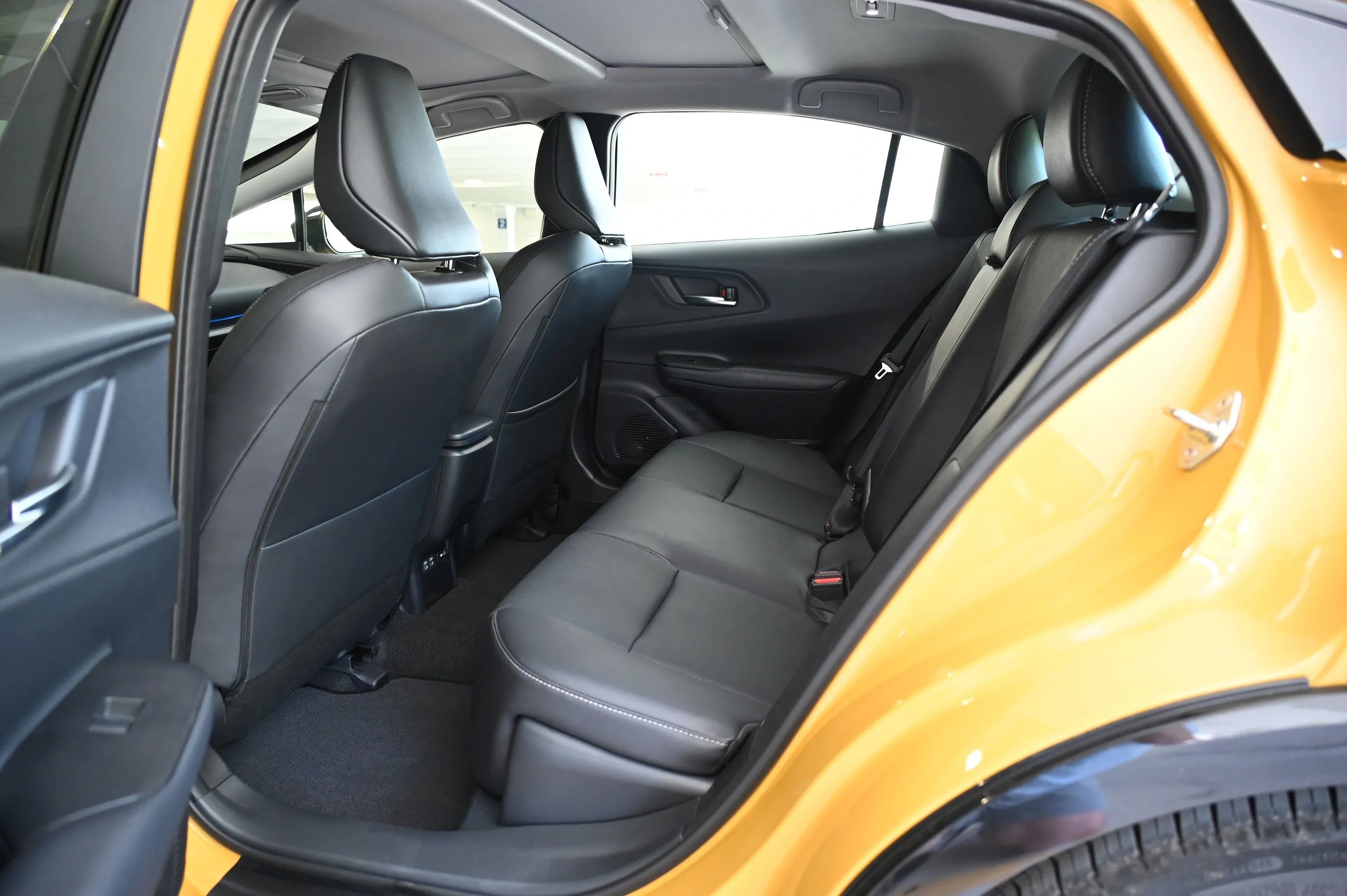 Rear passenger area of a Toyota Prius with black seats and open rear door.