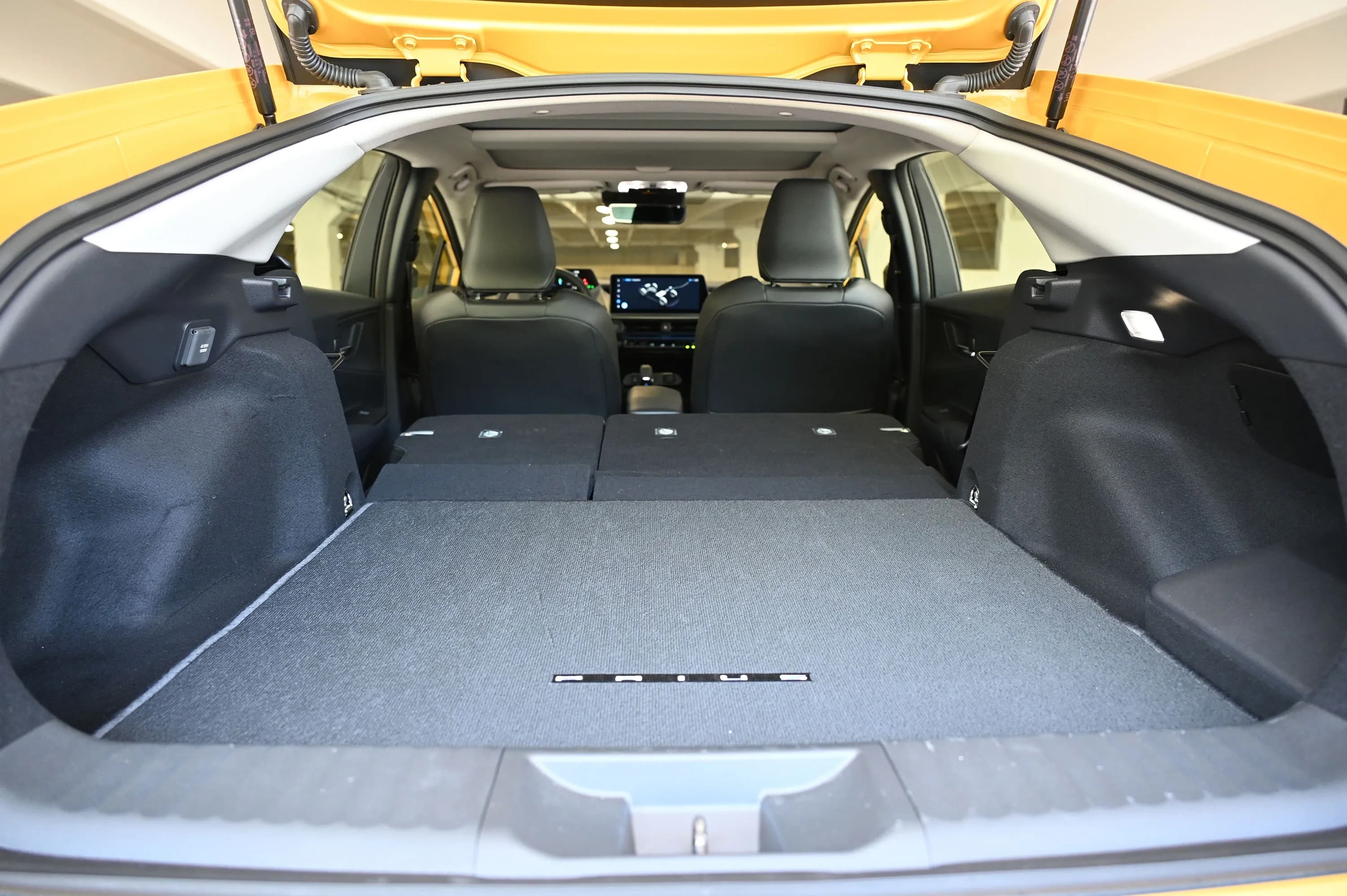 Rear cargo area of a Toyota Prius with the hatch open and the rear seats folded flat.
