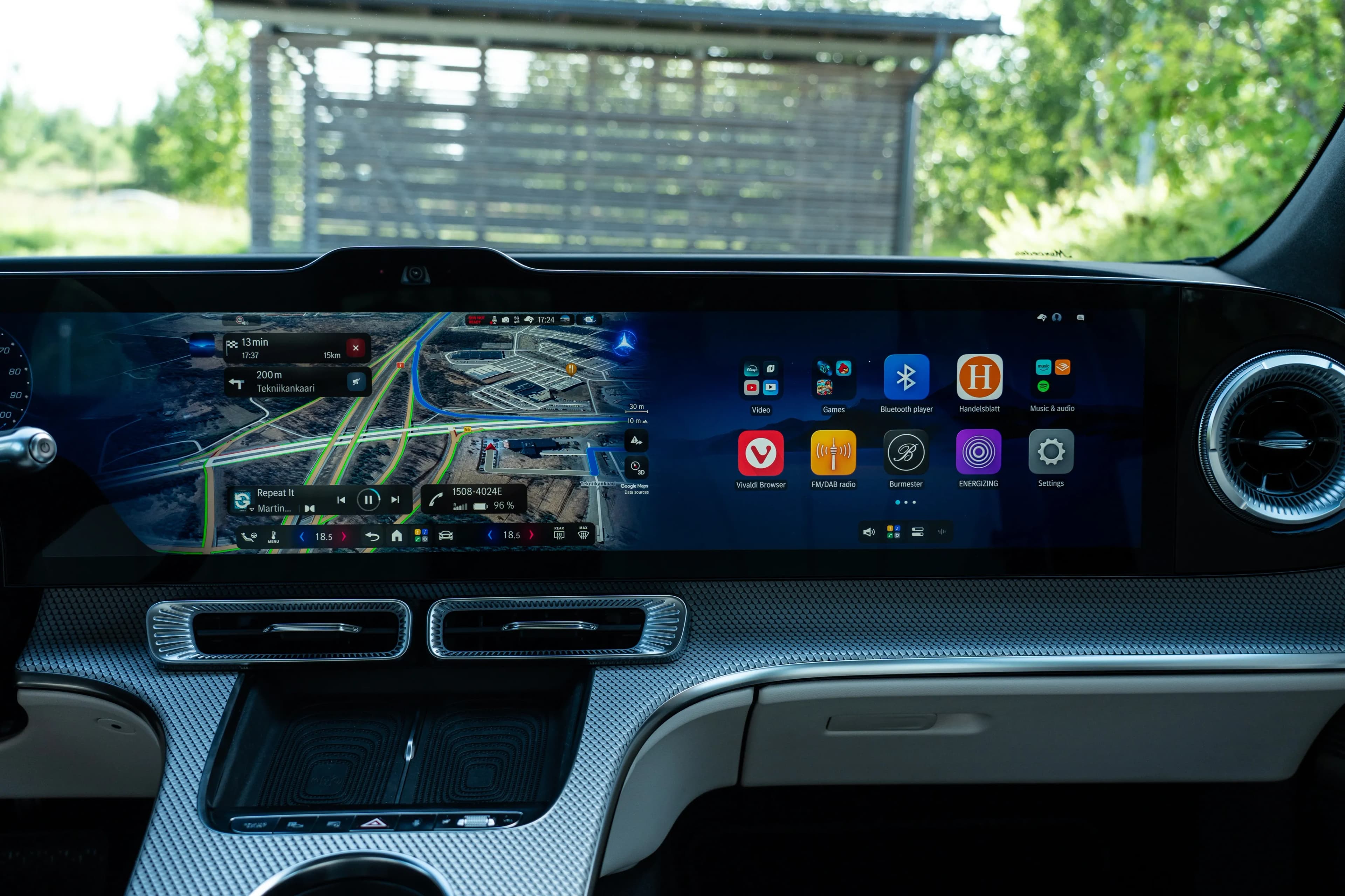 Pantalla panorámica del tablero con mapas de navegación e íconos de aplicaciones en el interior de un auto.