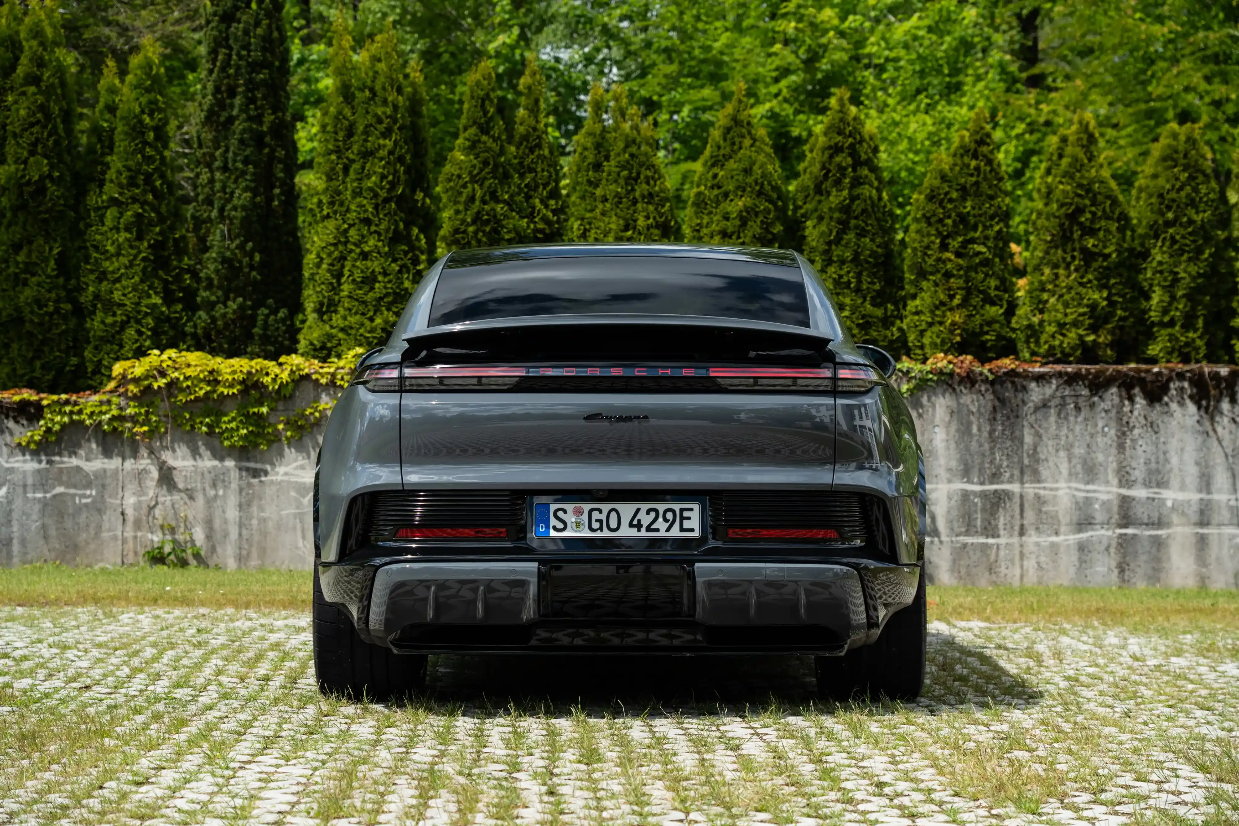 Vista trasera de una Porsche Cayenne Coupe Electric gris con una barra de luces traseras de ancho completo.