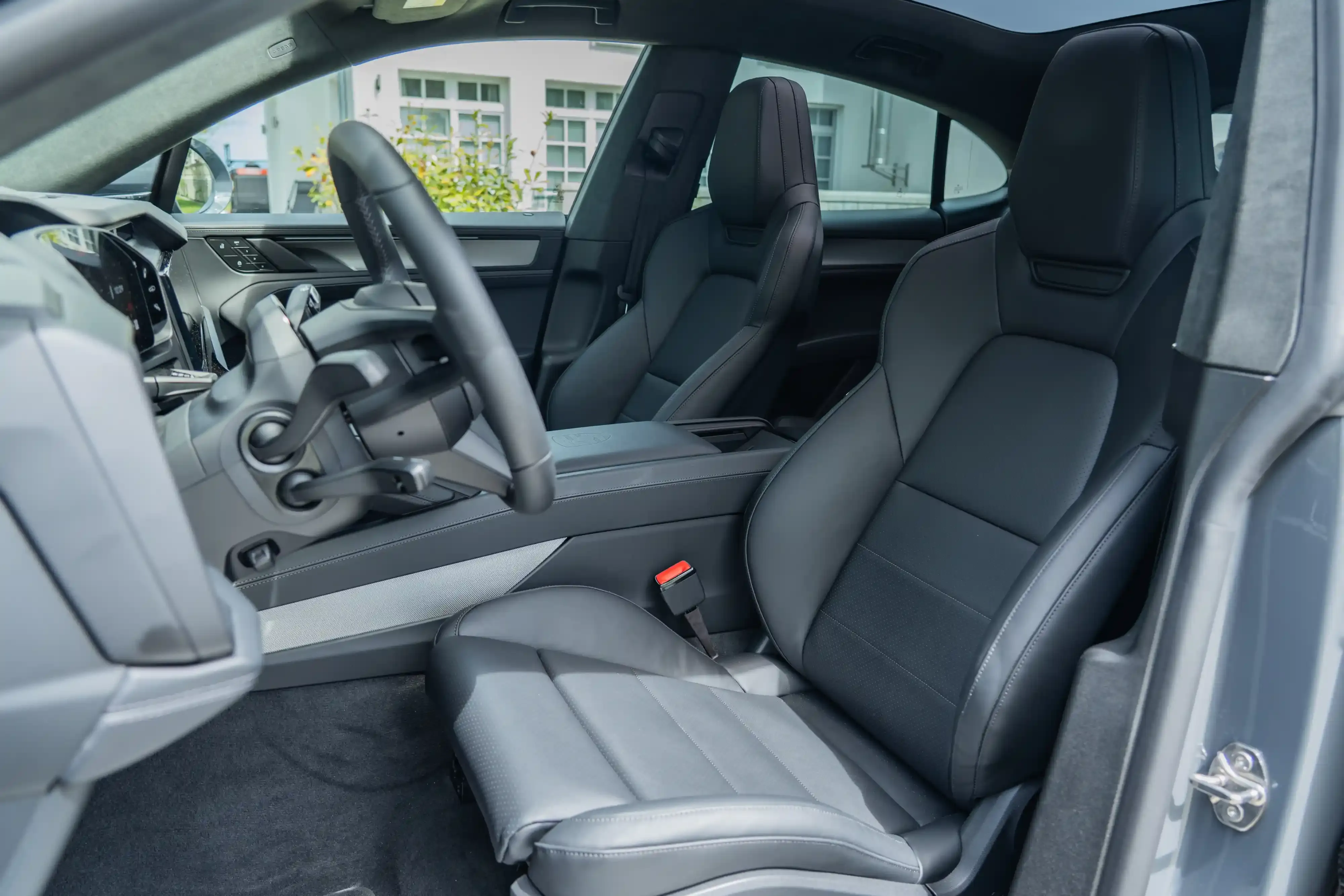 Cabina delantera de un Porsche Cayenne Coupe Electric con asientos tipo bucket negros y volante en forma de yugo.