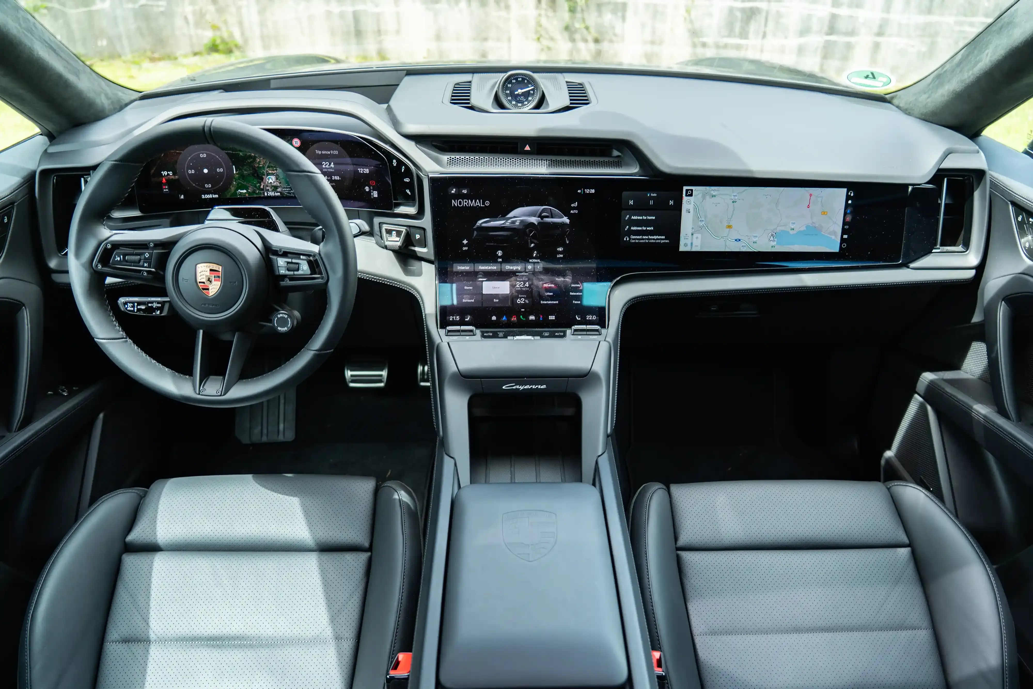 Interior delantero de un Porsche Cayenne con dos pantallas digitales y un apoyo para la muñeca en la consola central.