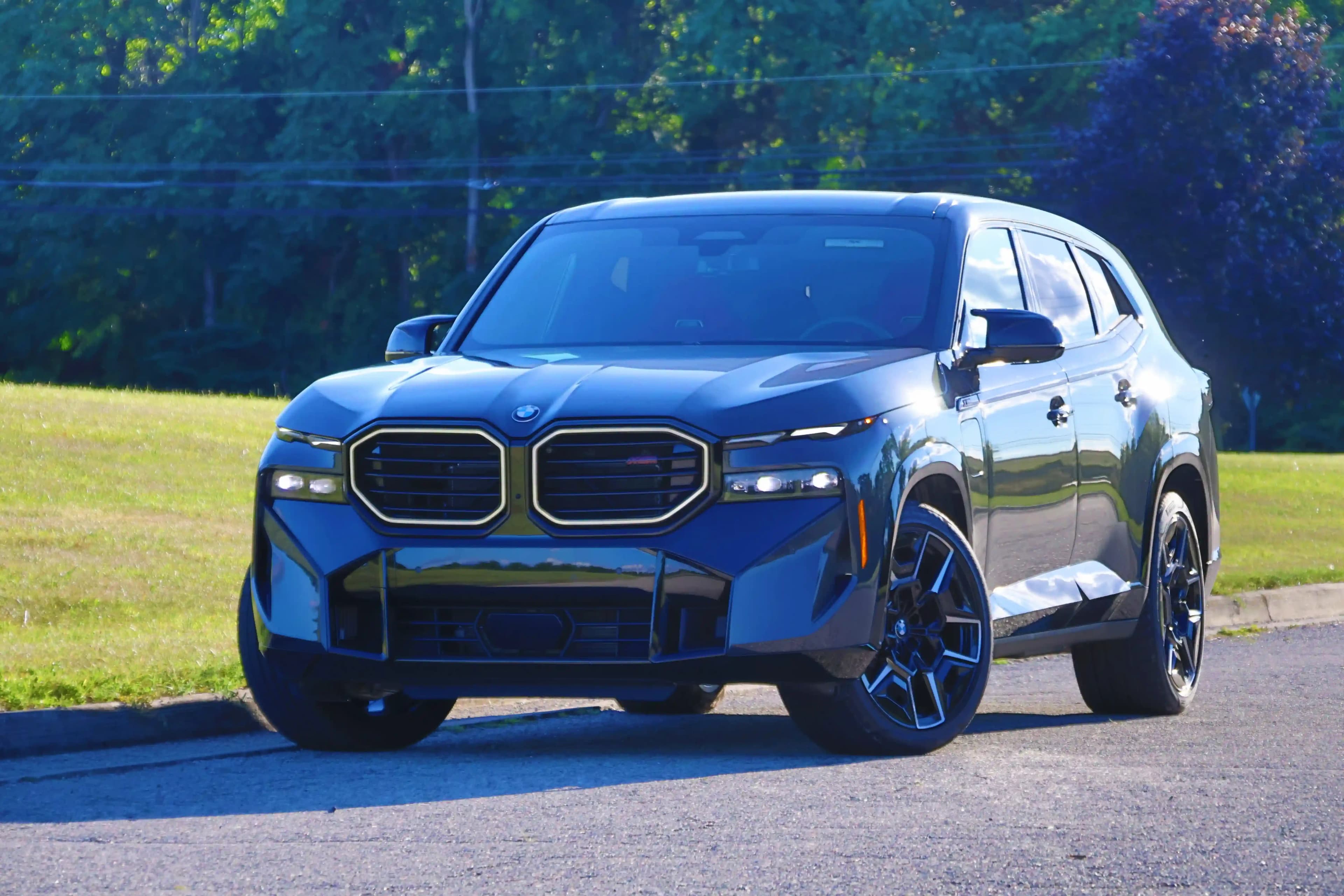 Front three-quarter view of a blue BMW XM parked on a road.