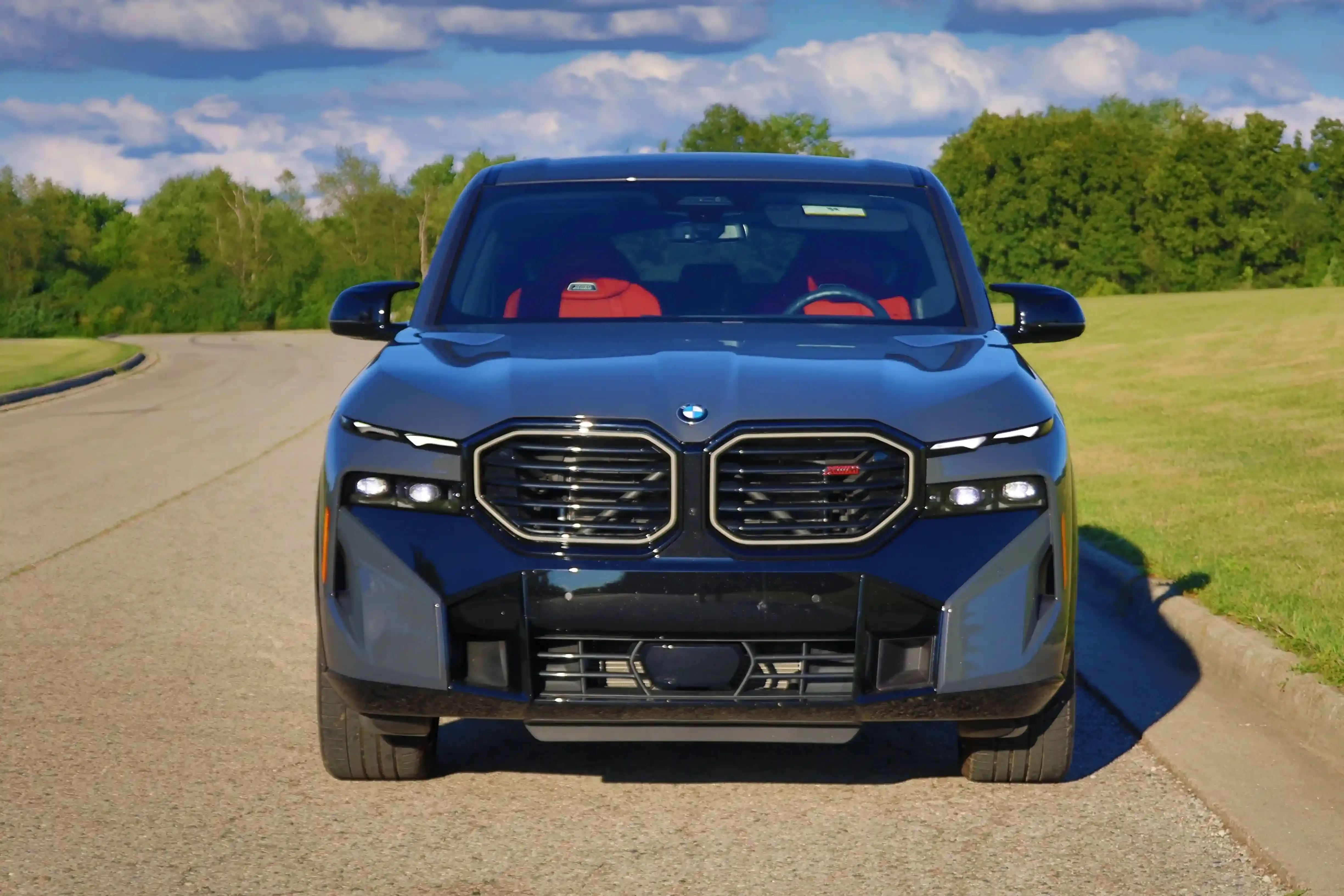 Front view of a blue BMW XM with red seats and large twin-kidney grille.