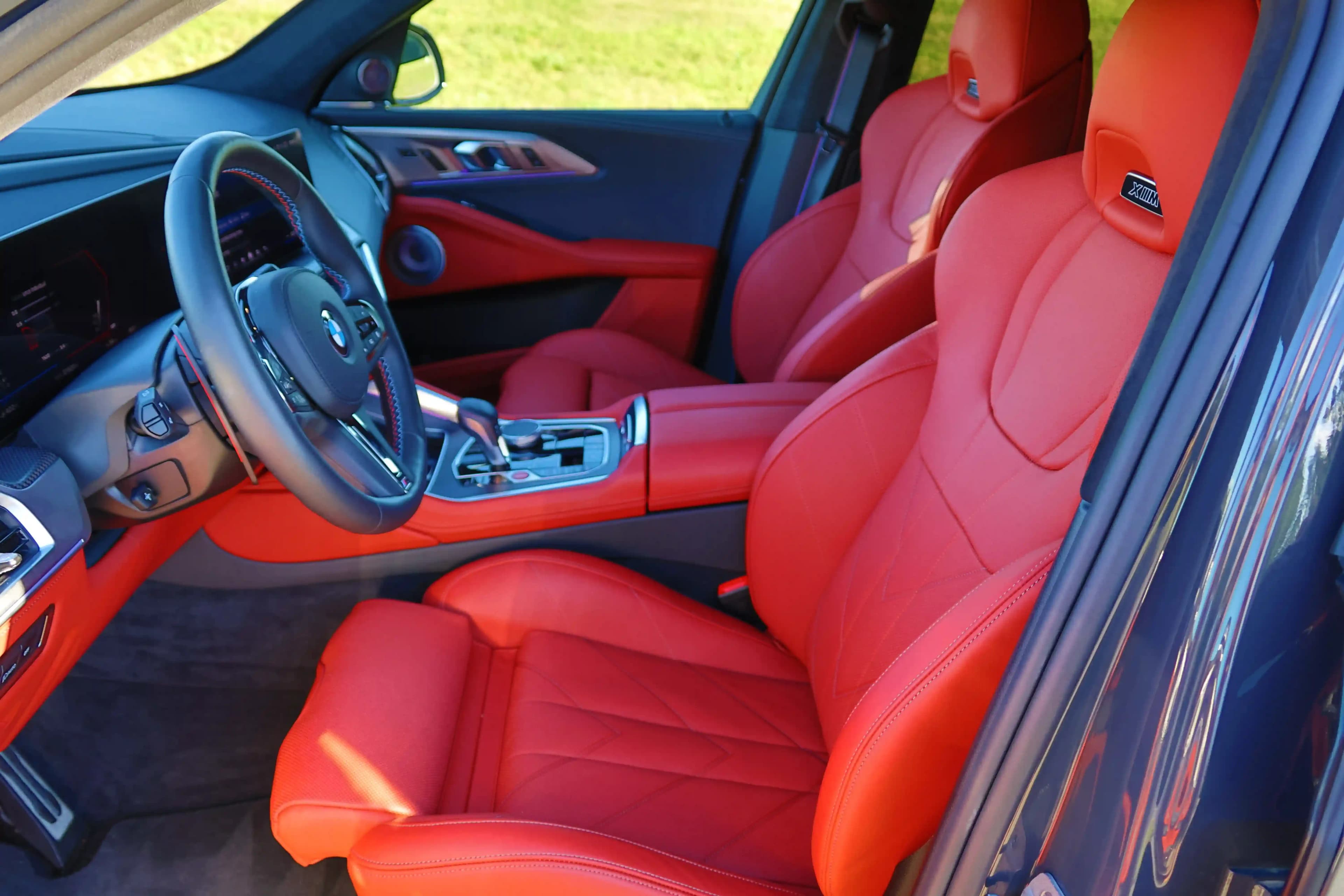 BMW XM interior with red leather front seats, steering wheel, and center console.