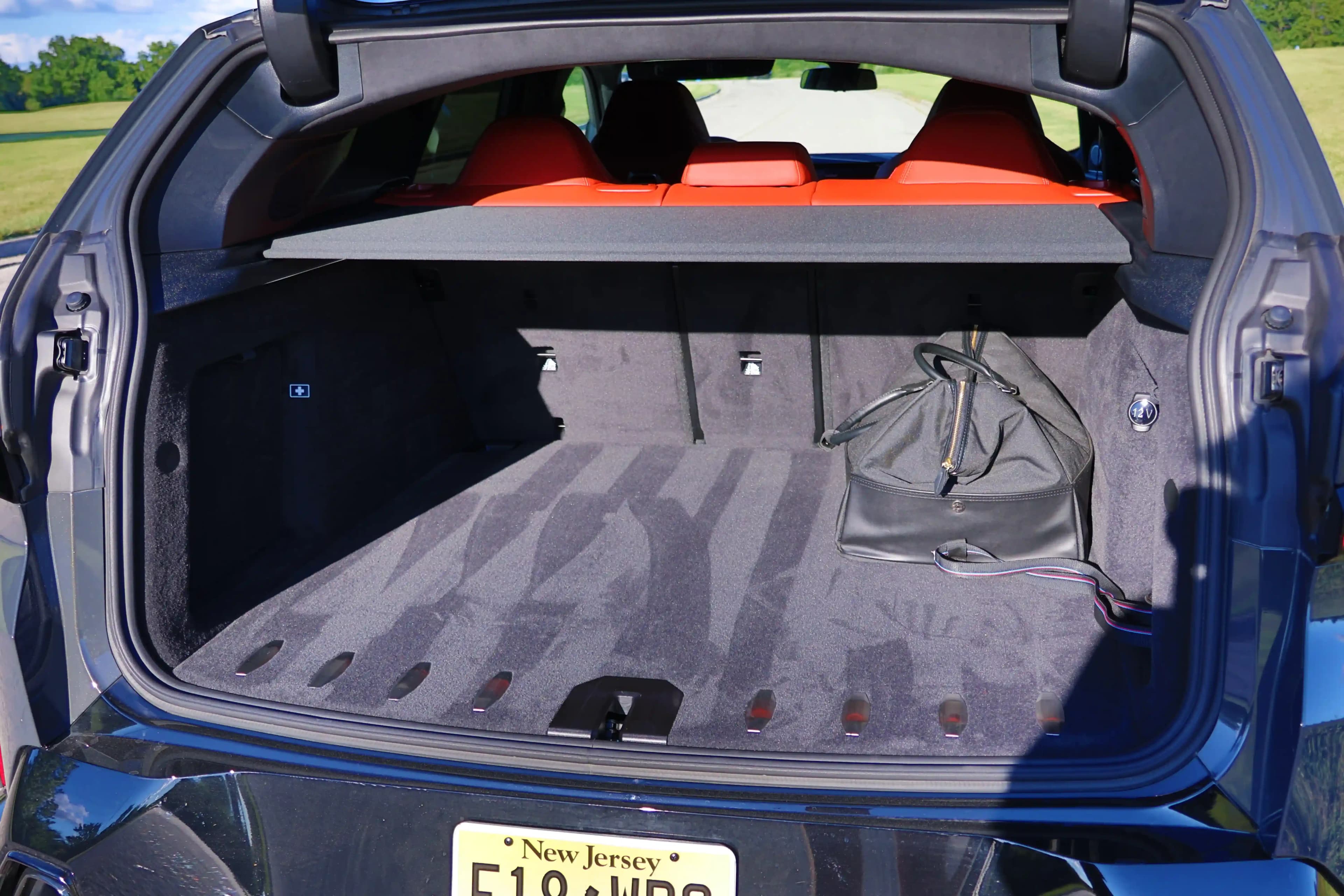 Open cargo area of a BMW XM with a bag inside and red rear seats visible.