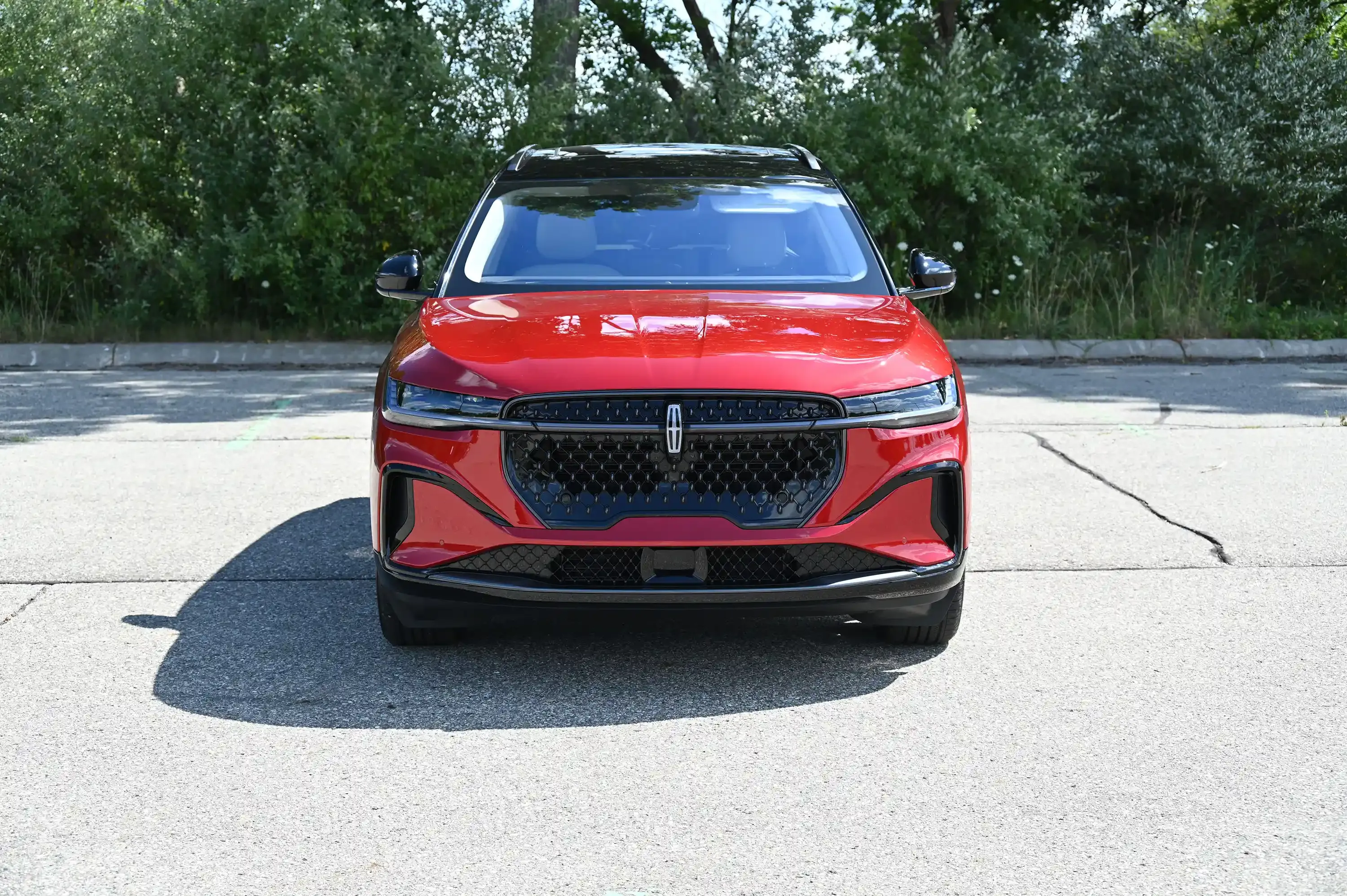 Vista frontal de un Lincoln Nautilus Hybrid rojo estacionado en una carretera.