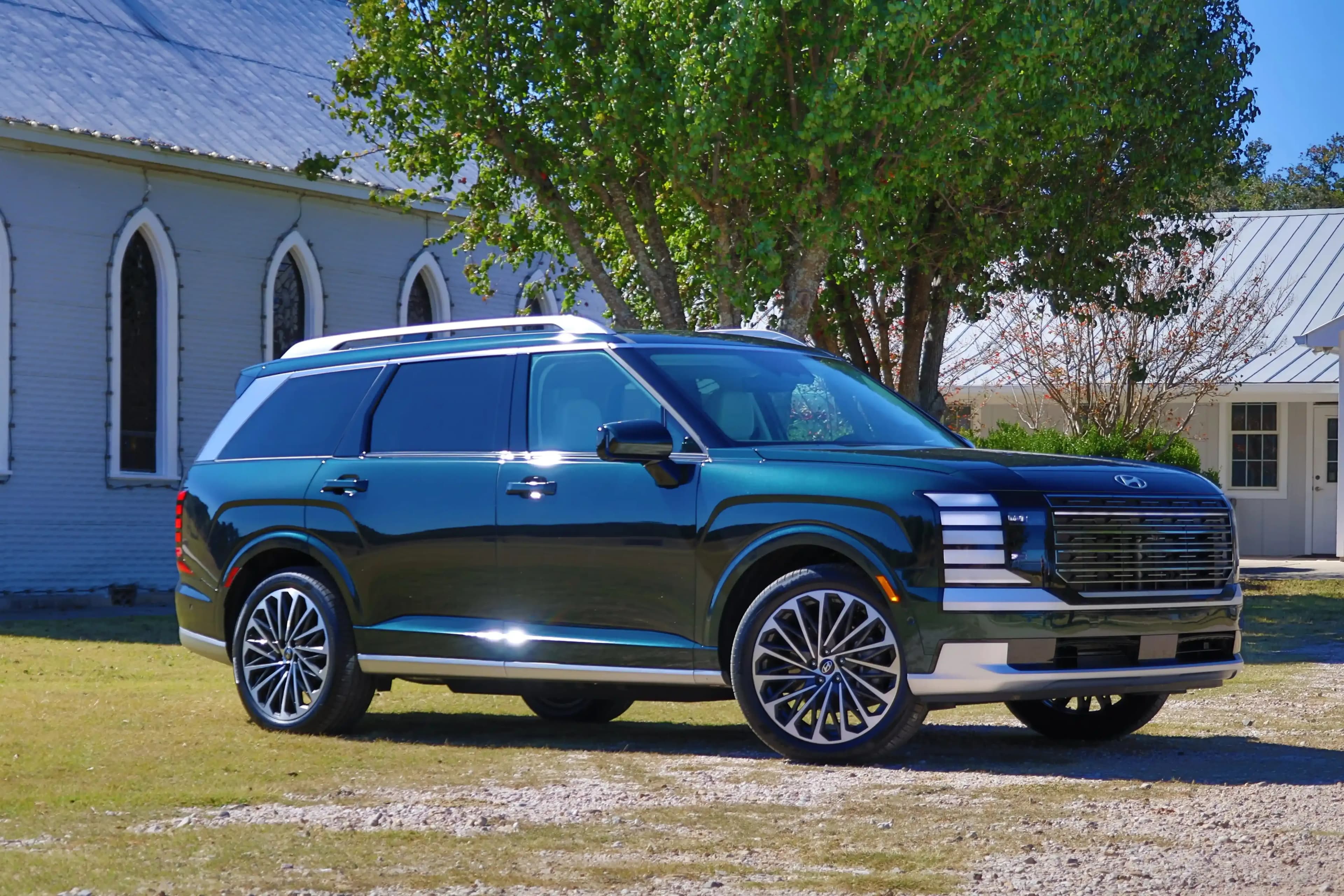 Side view of a Hyundai Palisade parked on grass outside a building.