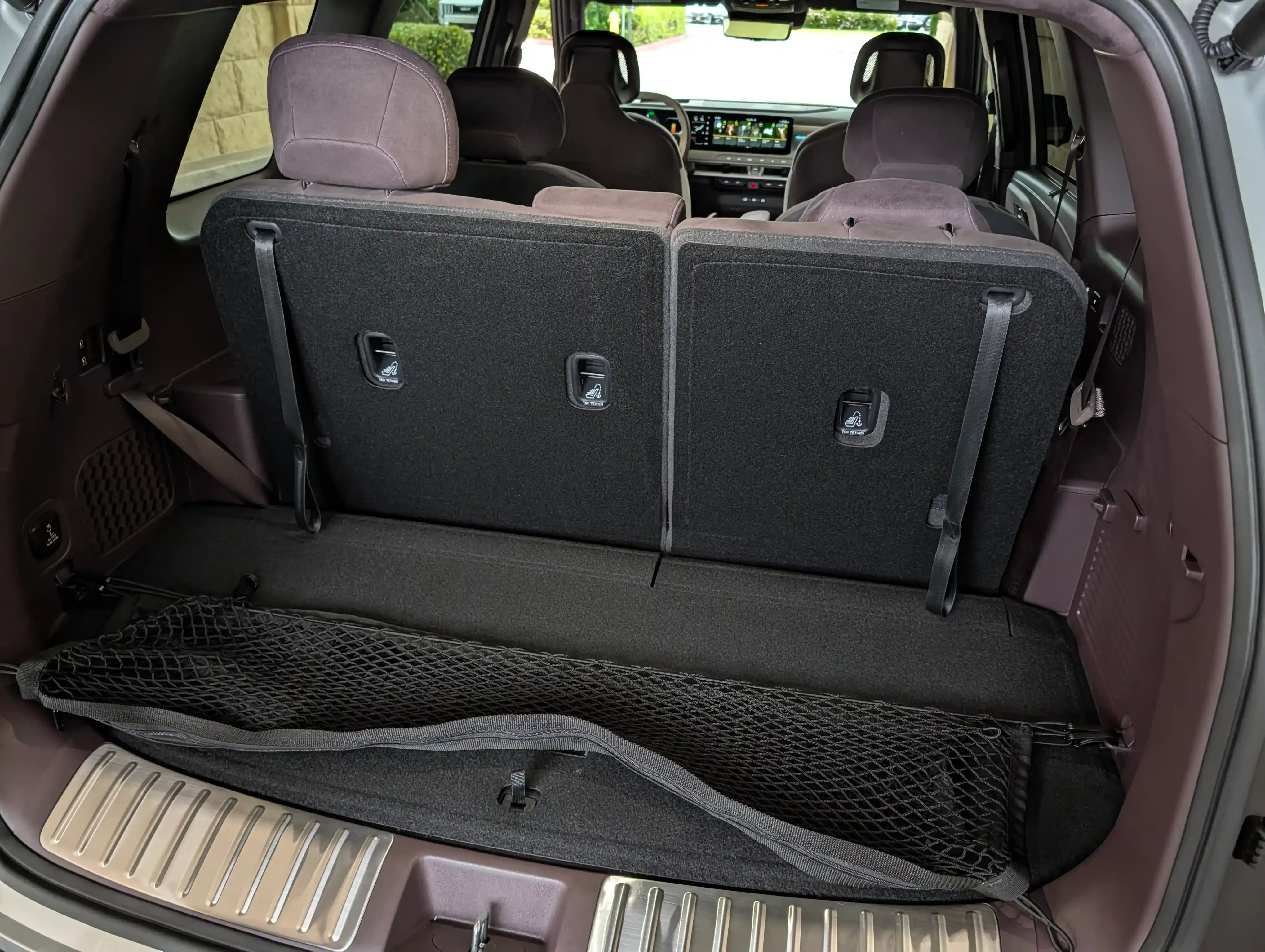 Rear cargo area with the third-row seats folded flat in a three-row SUV.