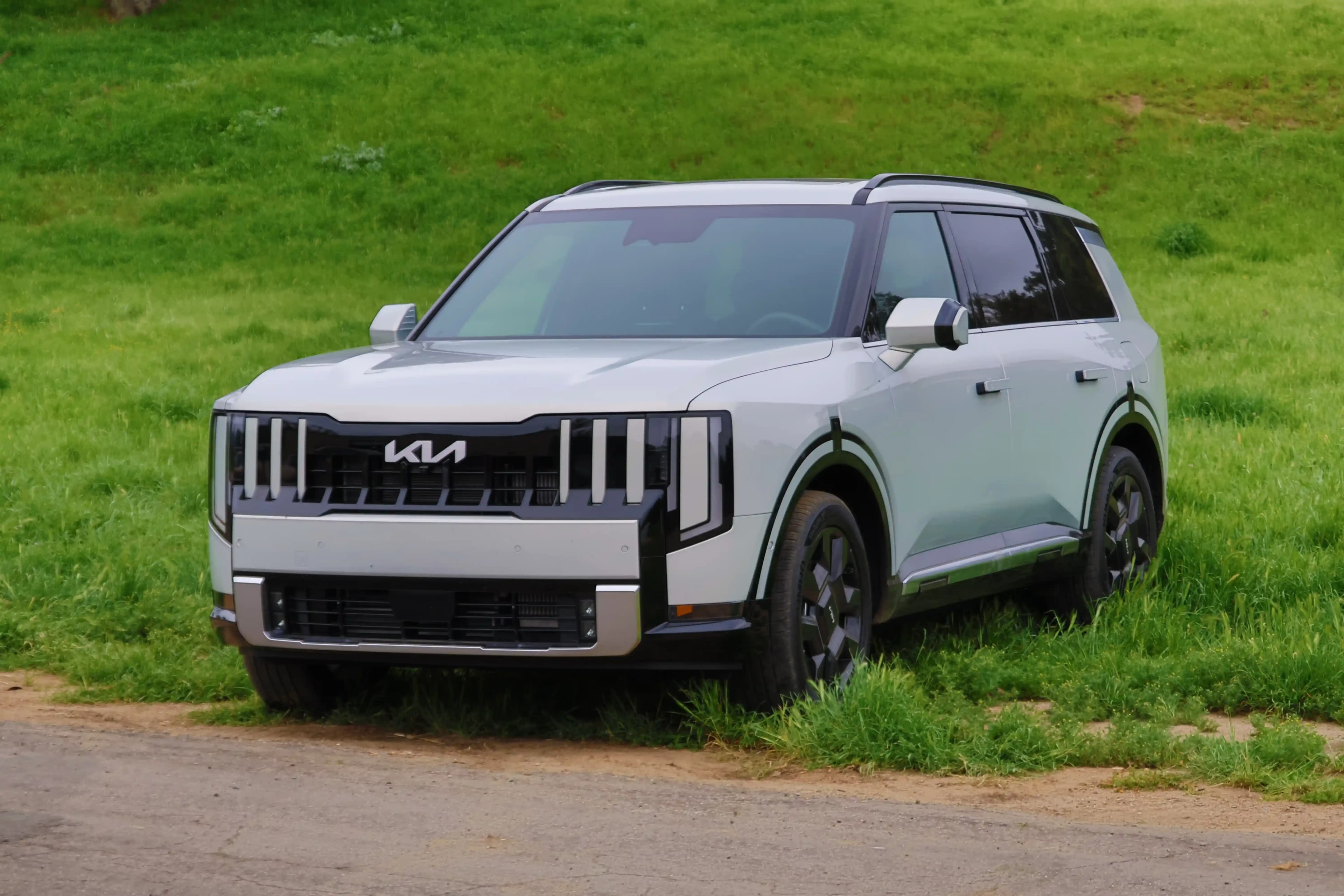 Front three-quarter view of a white Kia SUV parked on grass.